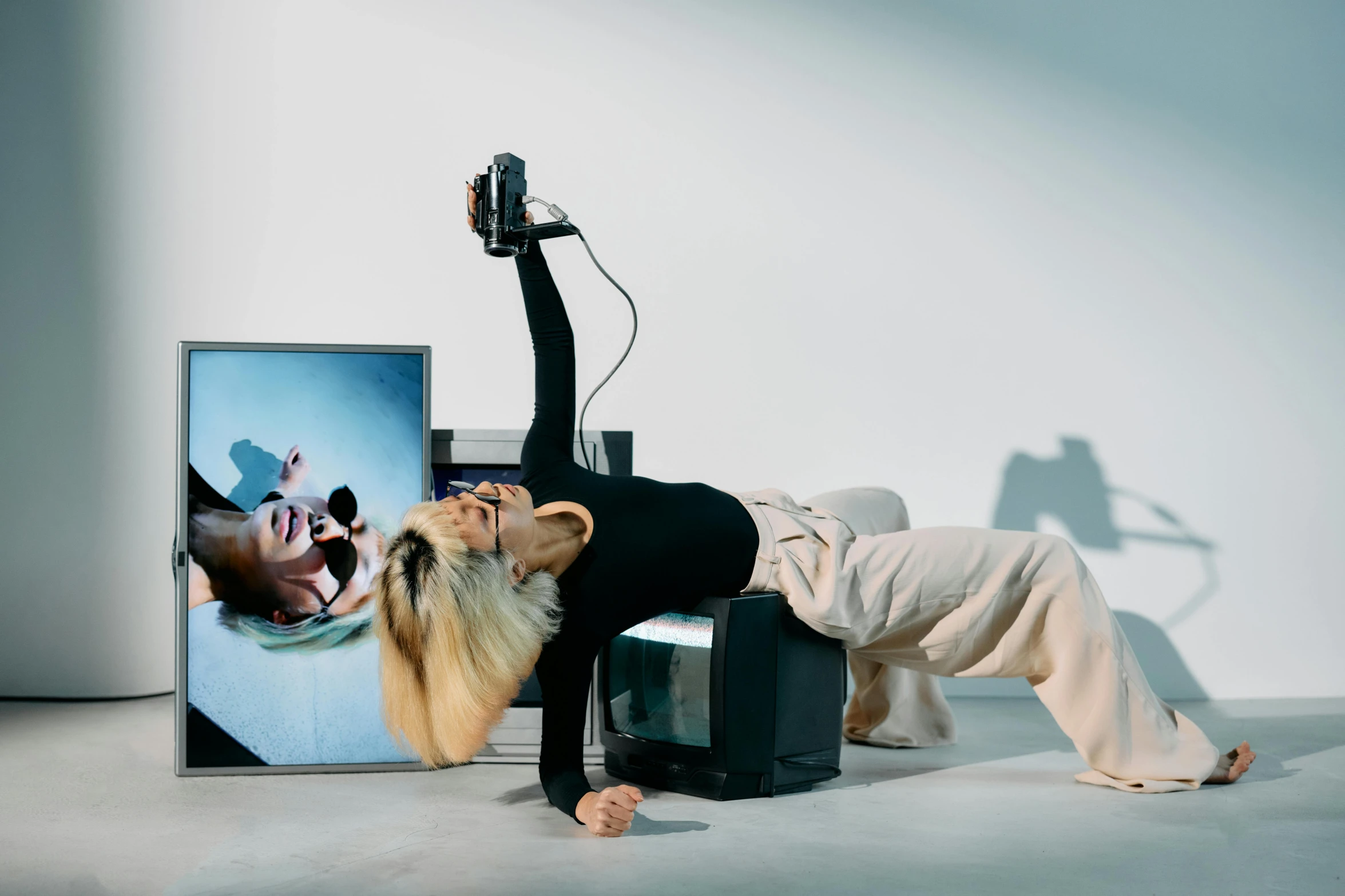 a woman doing a handstand in front of a television, a surrealist sculpture, inspired by Sarah Lucas, video art, portrait of kim petras, lying down, bang olufsen, headbanging