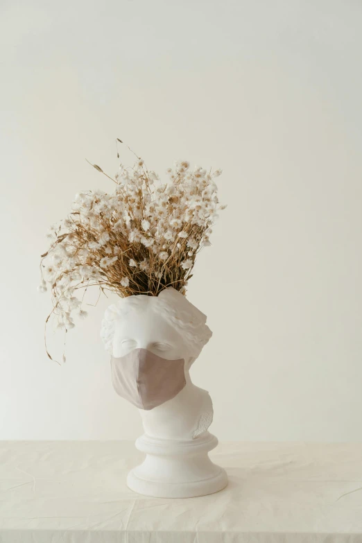 a vase with dried flowers in it on a table, a marble sculpture, by Liza Donnelly, unsplash, baroque, wearing white silk hood, with a white background, face mask, gypsophila