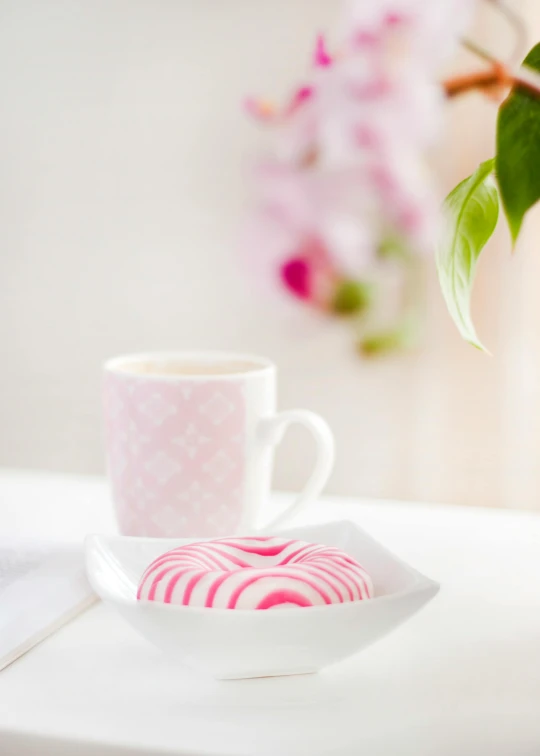 a cup of coffee and a donut on a table, inspired by Ödön Márffy, shutterstock contest winner, romanticism, white and pink, peppermint motif, shot with premium dslr camera, radiant soft light