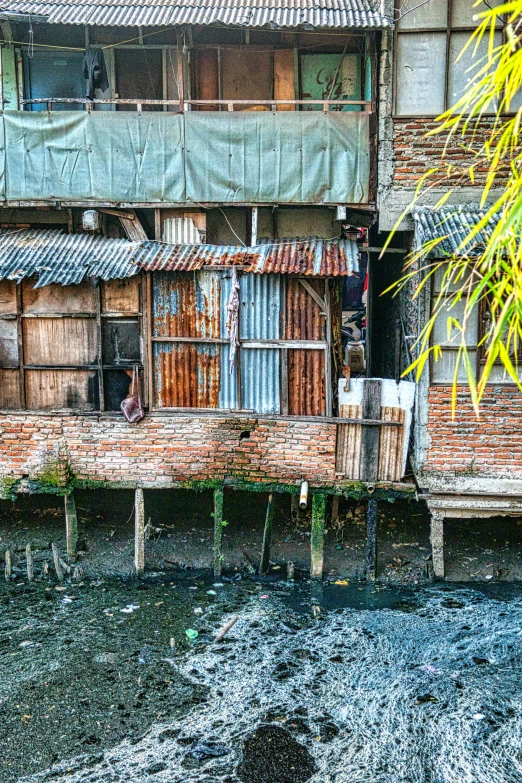 a building that is next to a body of water, inspired by Steve McCurry, pexels contest winner, slums, philippines, rustic and weathered, exterior
