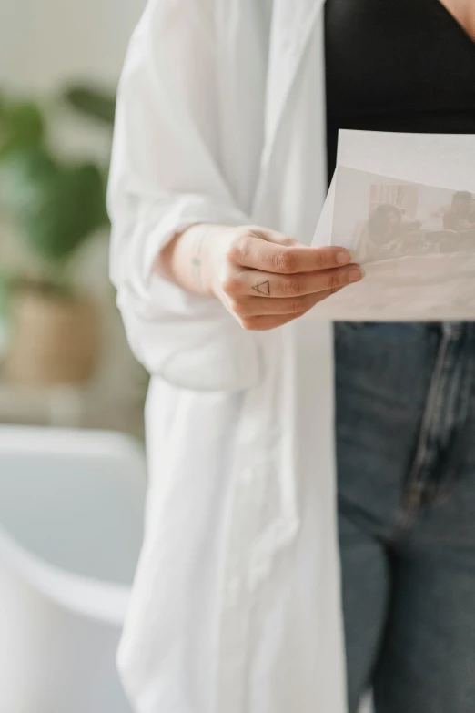 a woman holding a piece of paper in her hands, pexels contest winner, lab coat and tee shirt, exquisite details, healthcare, graphic print