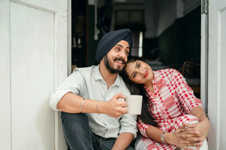 a man and a woman sitting next to each other, inspired by Manjit Bawa, pexels contest winner, with a white mug, 15081959 21121991 01012000 4k, leaning on door, joyful look