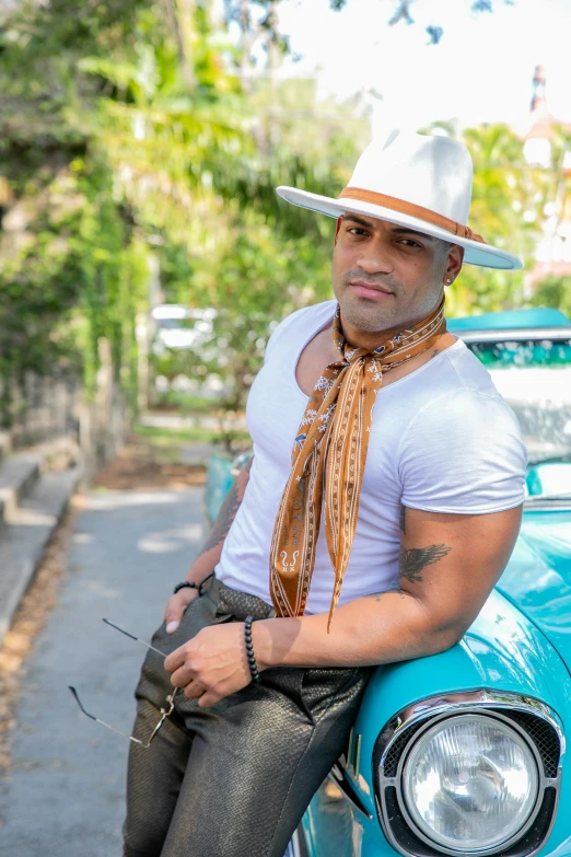 a man sitting on top of a blue car, an album cover, inspired by Byron Galvez, pexels contest winner, renaissance, white cowboy hat, puerto rican super hero, headshot profile picture, gay