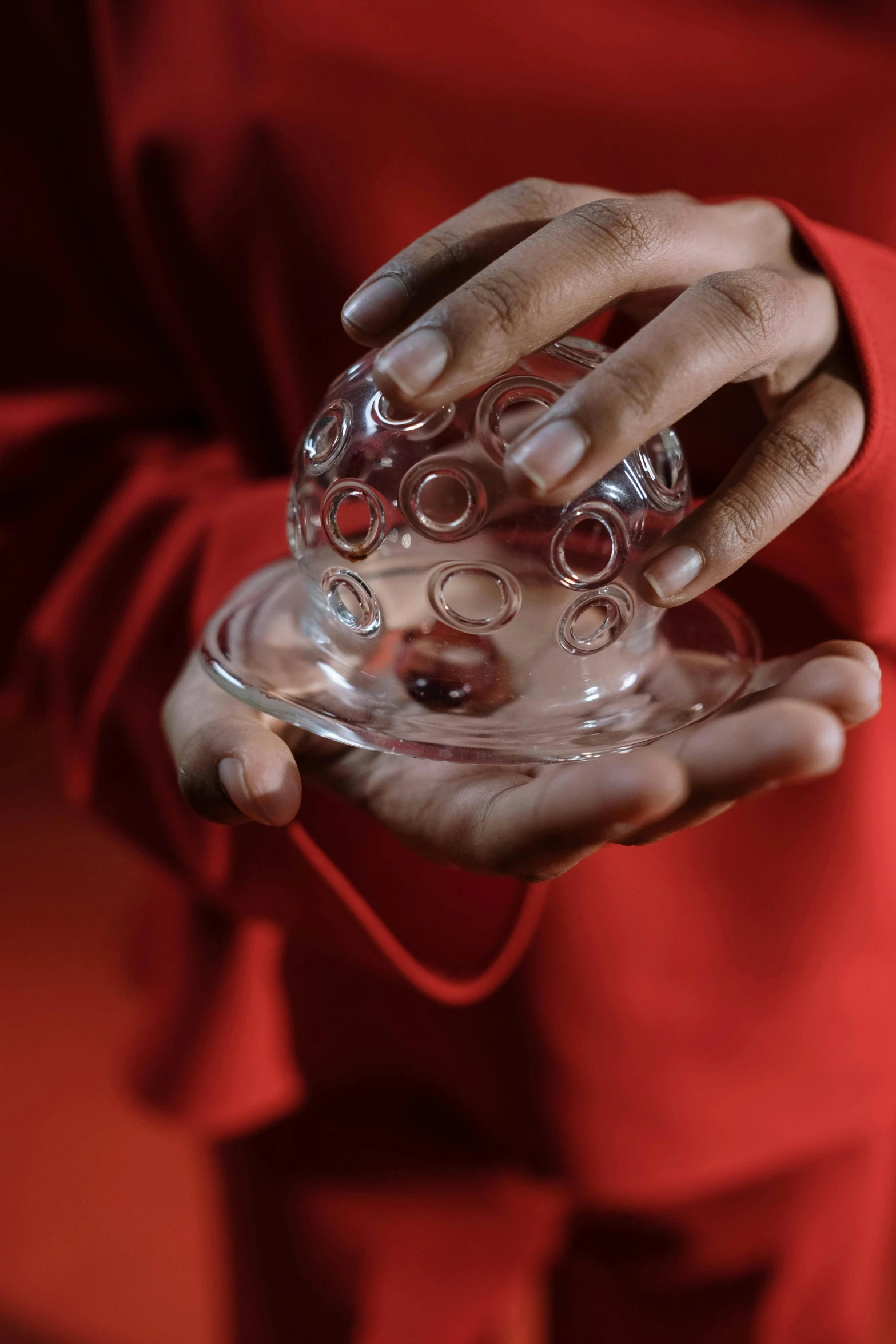 a close up of a person holding a glass, an album cover, inspired by Anish Kapoor, unsplash, hyperrealism, red dish, energy spheres, ignant, magician