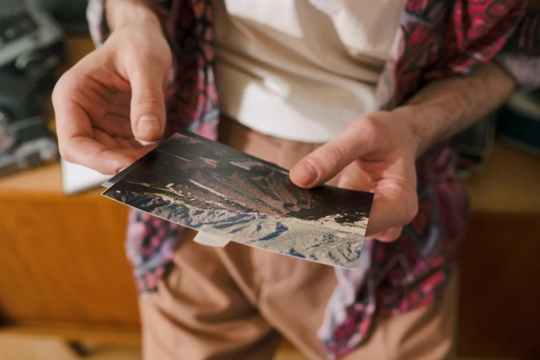 a man holding an old photo in his hands, pexels contest winner, panoramic anamorphic, colour print, close-up print of fractured, dixit card