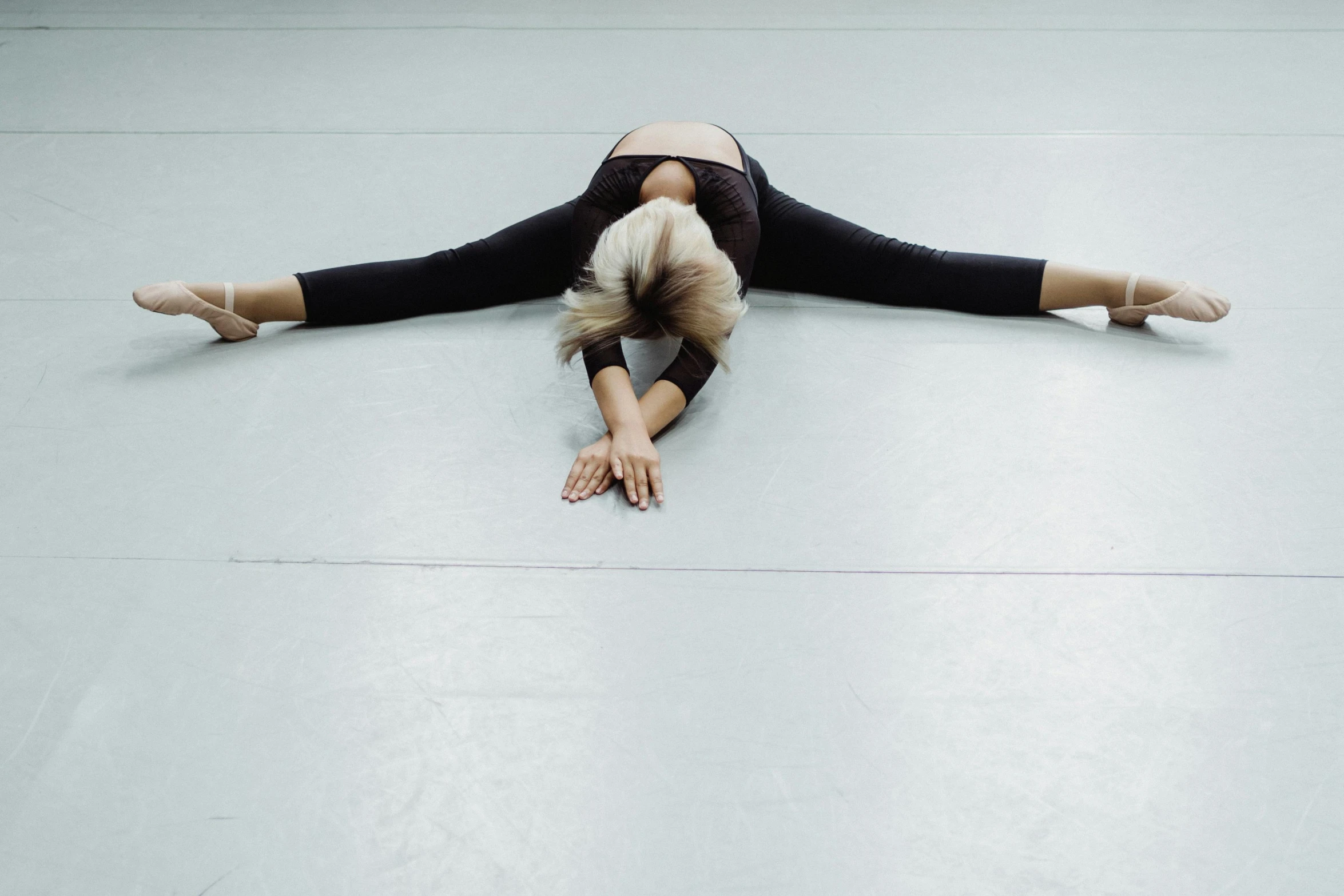 a woman in a black leo leo leo leo leo leo leo leo leo leo leo leo leo, by Nina Hamnett, unsplash, arabesque, doing splits and stretching, studio floor, face down, blank