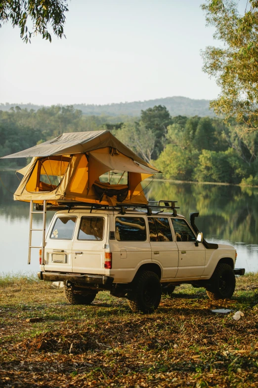 a truck parked next to a lake with a tent on top of it, yellow, square, null, vehicle profile