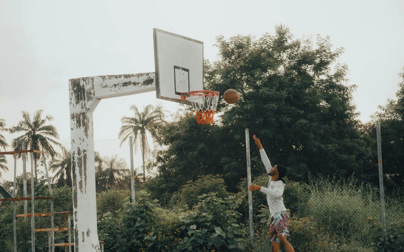 a man standing on top of a basketball court holding a basketball, by Carey Morris, pexels contest winner, dunking, 40 years old women, kids playing, flowers around