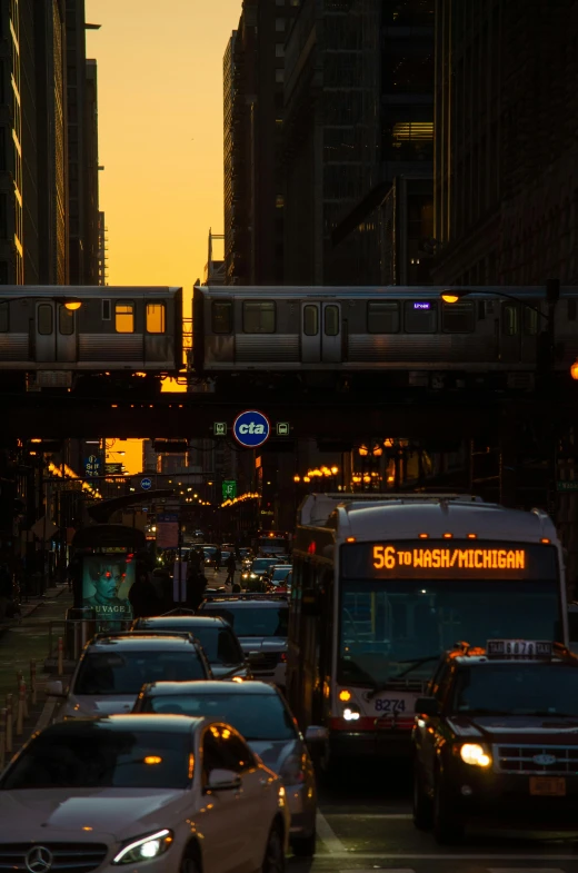 a city street filled with lots of traffic next to tall buildings, by Andrew Domachowski, backlit sunset, trains, chicago, suns