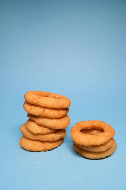 a stack of donuts sitting on top of a blue surface, two onion rings, photographed for reuters, square, warts