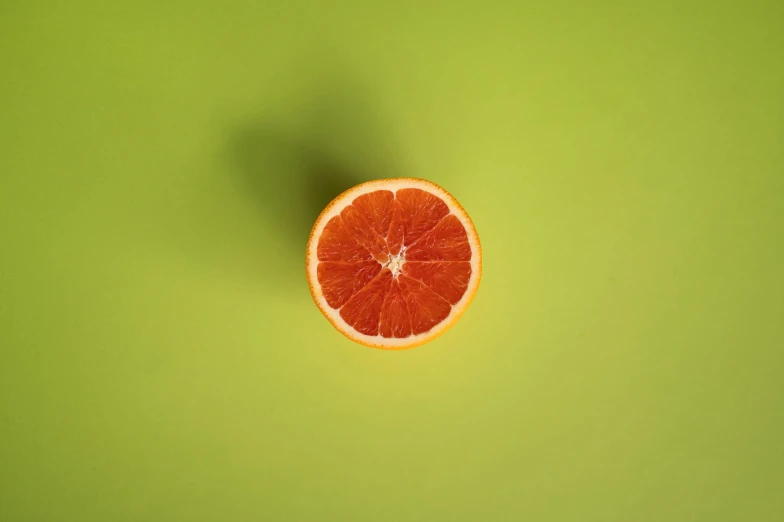 a grapefruit cut in half on a green surface, by Julian Allen, pexels contest winner, postminimalism, orange: 0.5, single color, vermillion, half moon