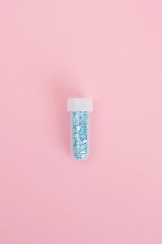 a bottle of glitter sitting on top of a pink surface, blue: 0.25, candy decorations, detailed product image, healing tubes
