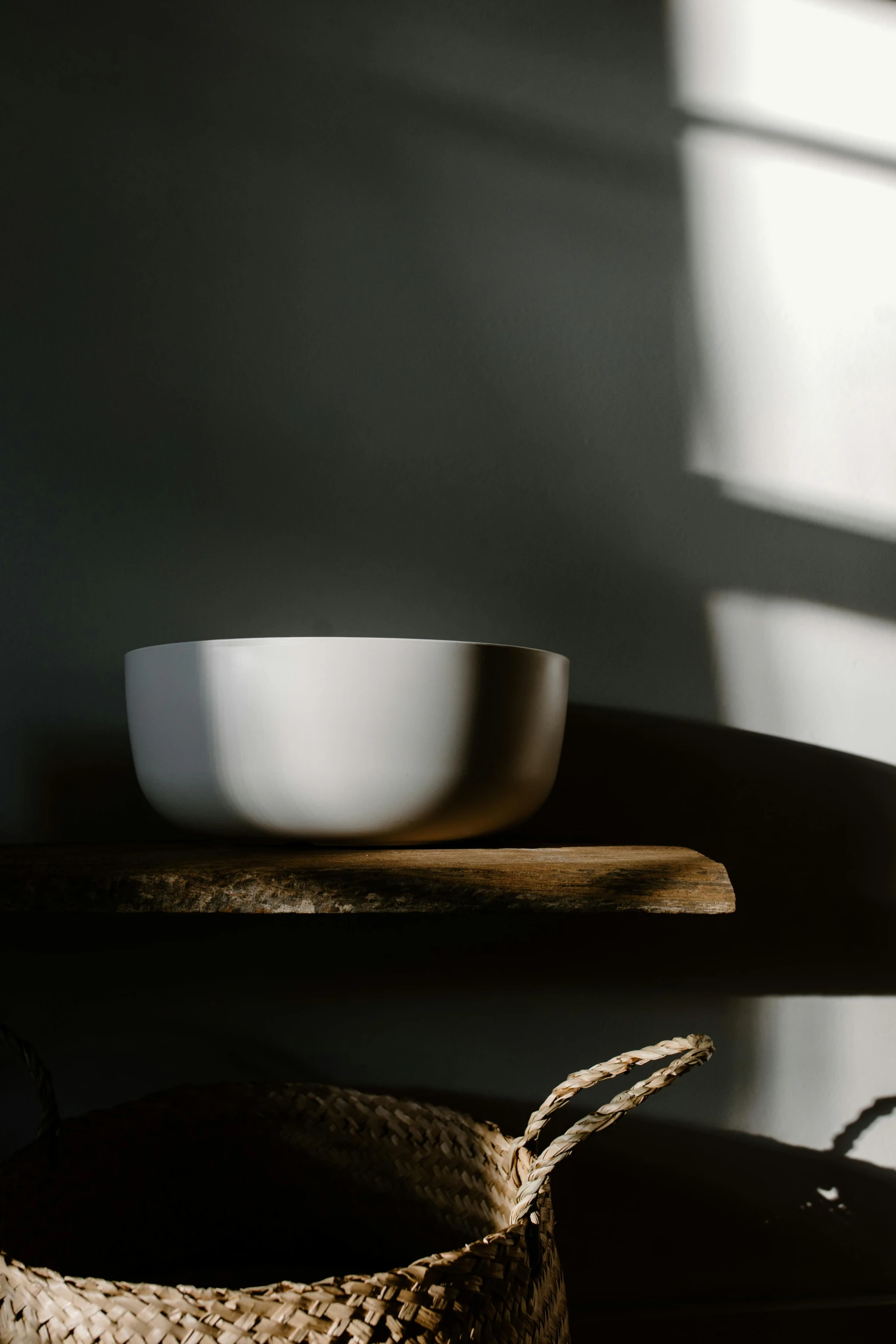 a white bowl sitting on top of a wooden table, inspired by Maciej Kuciara, minimalism, sunlight shining through, shelf, detailed product image, dimly lit