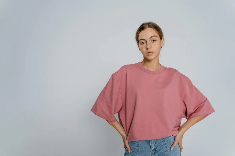 a woman standing with her hands in her pockets, inspired by Julius Klinger, trending on pexels, hyperrealism, pink shirt, dolman, wearing crop top, dull red