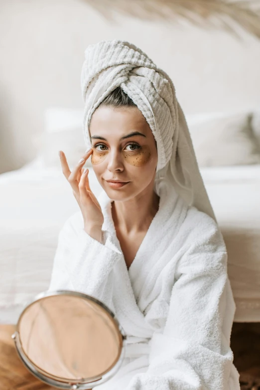 a woman sitting on the floor with a towel on her head, a picture, by Julia Pishtar, trending on pexels, renaissance, dark circles under bemused eyes, gold and white robes, skincare, bedroom eyes