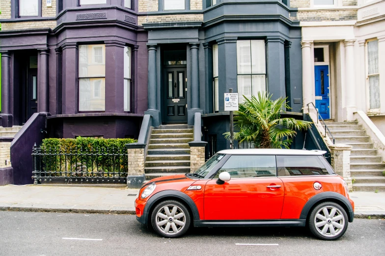 a red car parked in front of a purple house, by Nina Hamnett, pexels contest winner, mini cooper s, in london, black and orange, 1811