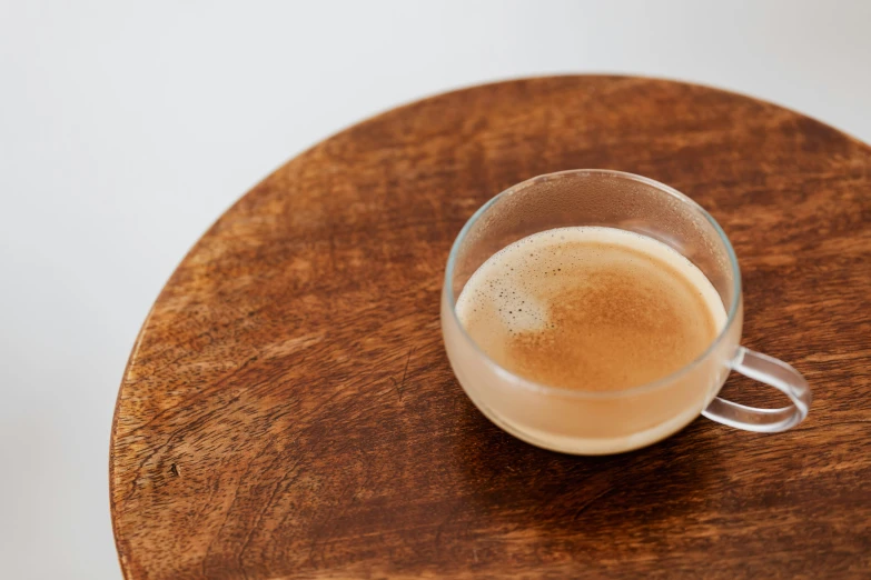 a cup of coffee sitting on top of a wooden table, inspired by Richmond Barthé, light tan, dewy skin, engineered, medium - shot