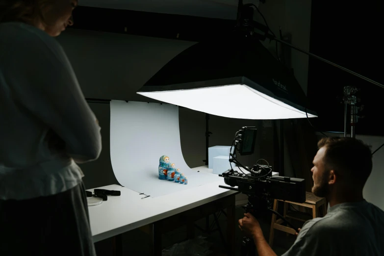 a man standing next to a woman in front of a light, unsplash contest winner, hyperrealism, toy commercial photo, curved. studio lighting, claymation, person in foreground