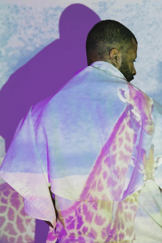 a man standing in front of a painting of a giraffe, an album cover, inspired by Barkley Hendricks, unsplash, wearing torn white cape, diaphanous iridescent silks, kayne west, seen from the back