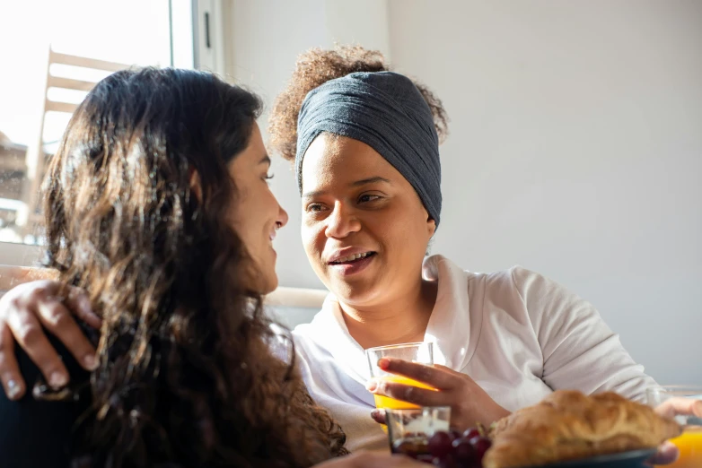 two women sitting at a table sharing a meal, a portrait, trending on pexels, someone in home sits in bed, avatar image, wearing a headband, aida muluneh