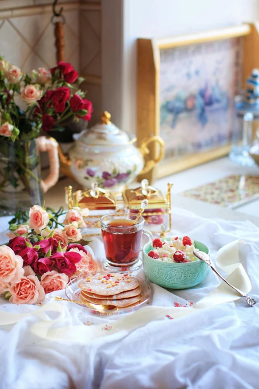 a table topped with a plate of food next to a vase of flowers, by Annabel Kidston, rococo, moroccan tea set, raspberry, rose twining, profile pic