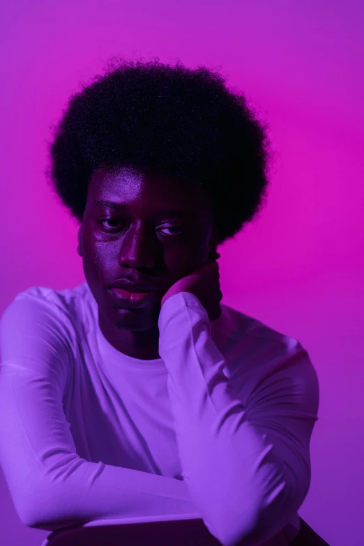 a man sitting on a chair in front of a purple background, by Winona Nelson, pexels contest winner, afrofuturism, black man with afro hair, barely lit warm violet red light, standing with a black background, adut akech