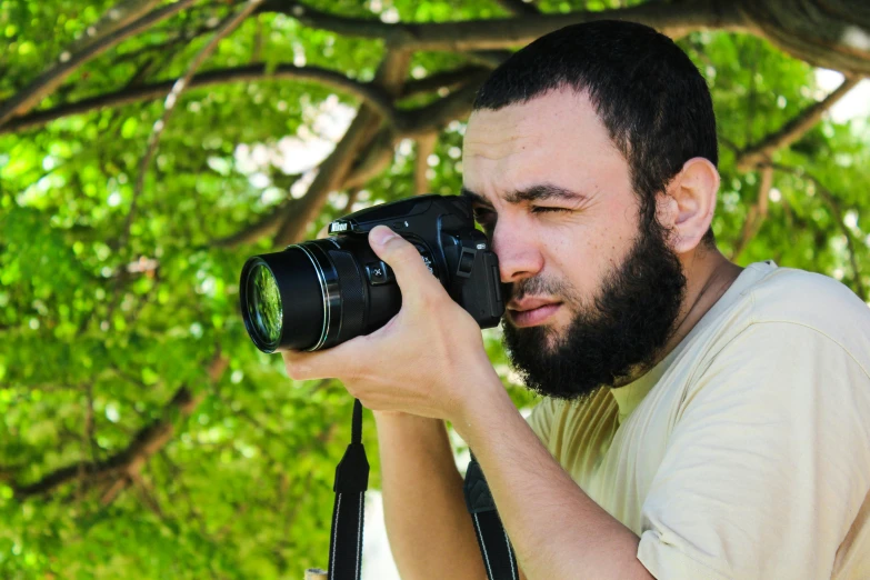 a man taking a picture with a camera, by Farid Mansour, focused expression, islamic, high-quality dslr photo”, avatar image