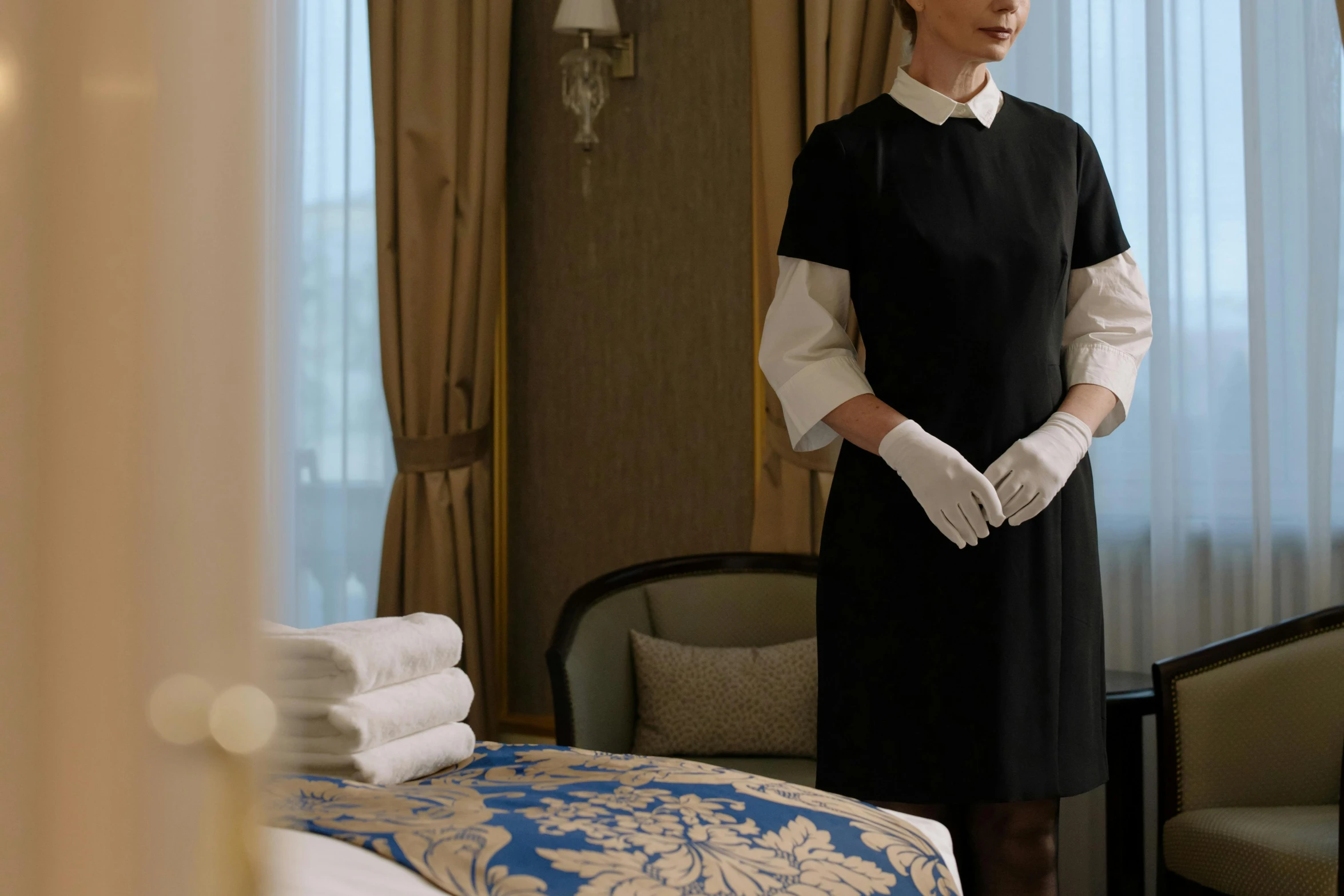 a woman standing in a hotel room next to a bed, live-action adaptation, gilded black uniform, [ theatrical ]