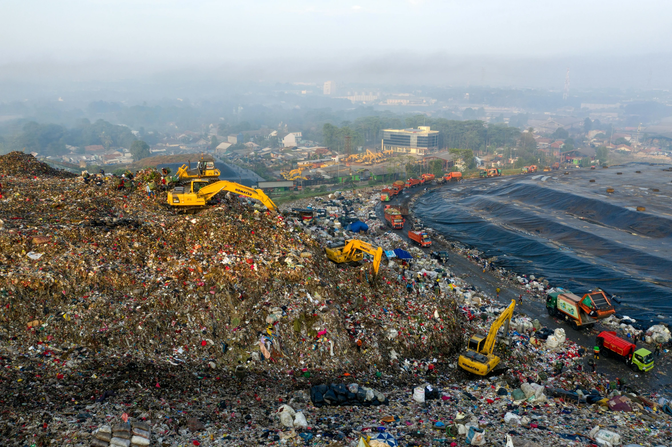 a large pile of garbage next to a body of water, full of people, yellow, avatar image, massive construction machines