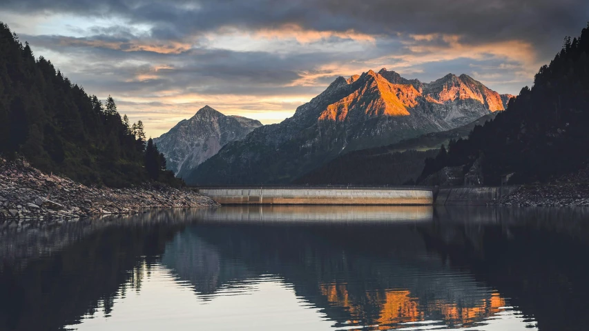 a body of water with mountains in the background, by Franz Hegi, pexels contest winner, sunset lighting, fan favorite, wall of water either side, alpes