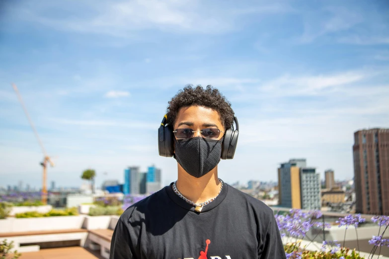 a man wearing headphones standing on top of a roof, wearing all black mempo mask, mkbhd, avatar image, environmental shot