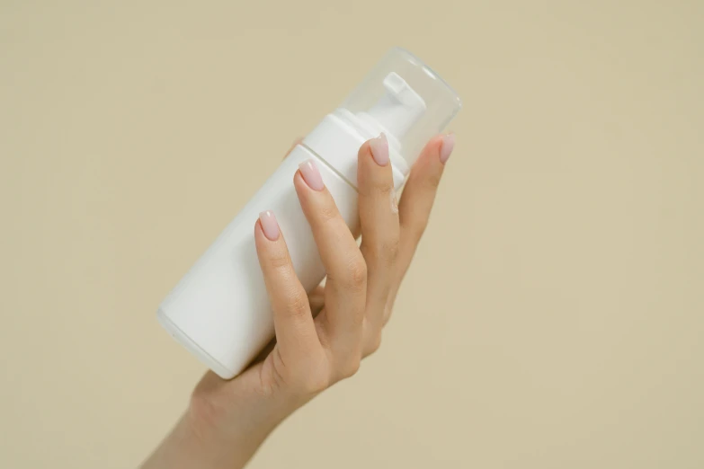 a woman holding a bottle of lotion in her hand, unsplash, minimalism, with electric arc device, background image, foam, animation