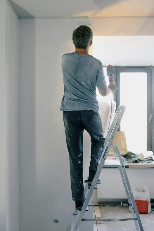 a man that is standing on a ladder, a painting, pexels, interiors, on grey background, gif, pants