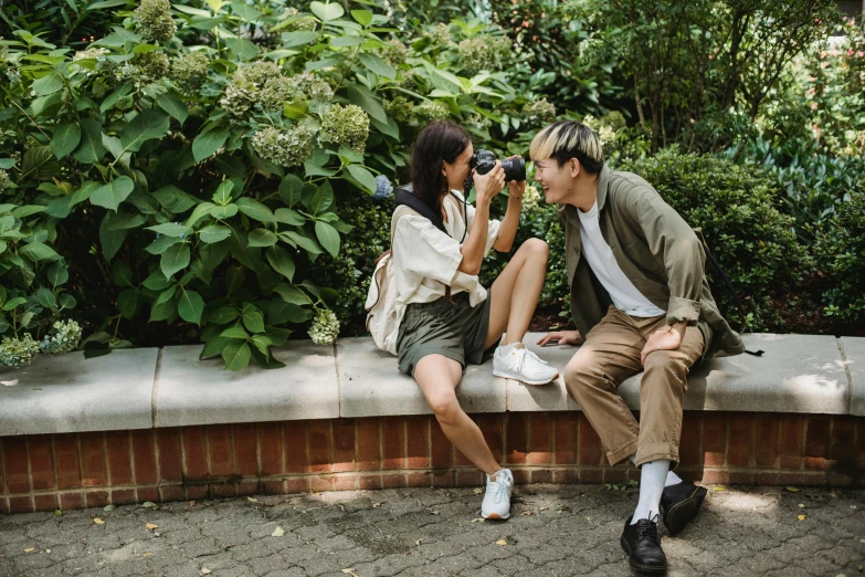 a man and woman sitting next to each other on a bench, a picture, pexels contest winner, with nikon cameras, standing in a botanical garden, gemma chen, playful pose