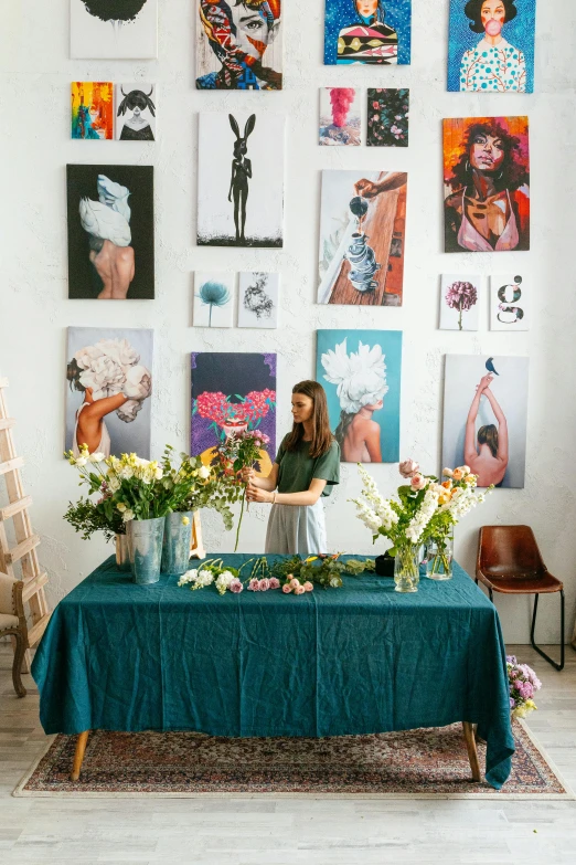 a woman standing in front of a table with flowers, poster art, trending on pexels, process art, with teal clothes, gallery display photograph, decoration around the room, professional picture