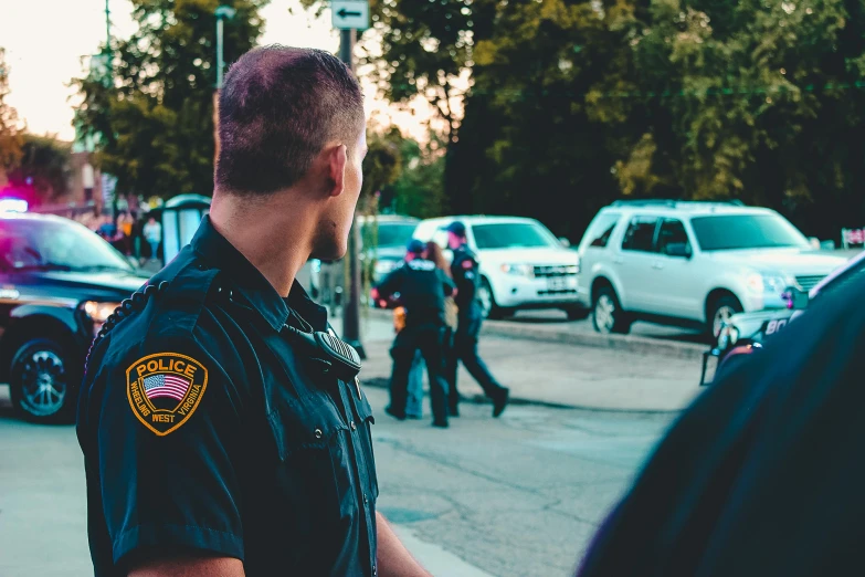 a police officer standing in the middle of a street, pexels, happening, diverse, looking left, neighborhood, 🚿🗝📝