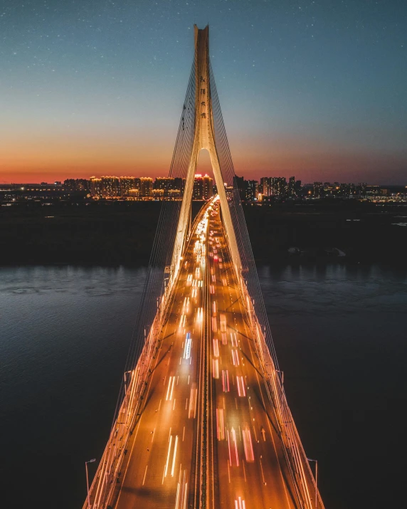 a long bridge over a body of water at night, by Adam Marczyński, pexels contest winner, flying over a city, highway and sunset!!, lgbtq, symmetrical image