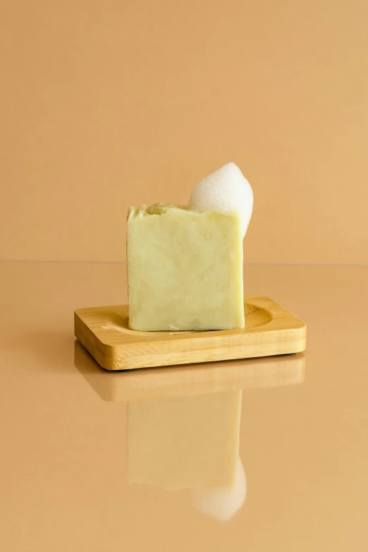 a soap bar sitting on top of a wooden tray, by Jessie Algie, renaissance, pastel green, mozzarella, soft spot light, sassy pose