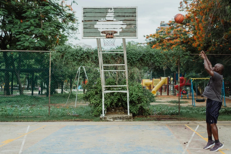 a man standing on top of a basketball court holding a basketball, by Elsa Bleda, unsplash contest winner, hyperrealism, children playground, parks and gardens, sri lanka, 15081959 21121991 01012000 4k