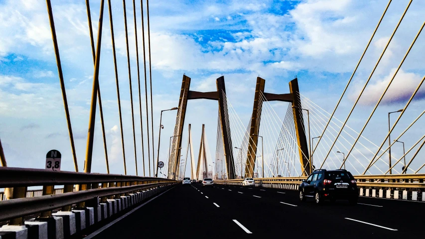 a car driving across a bridge on a cloudy day, by Ceferí Olivé, pexels contest winner, calcutta, beautiful sunny day, tall structures, connecting lines