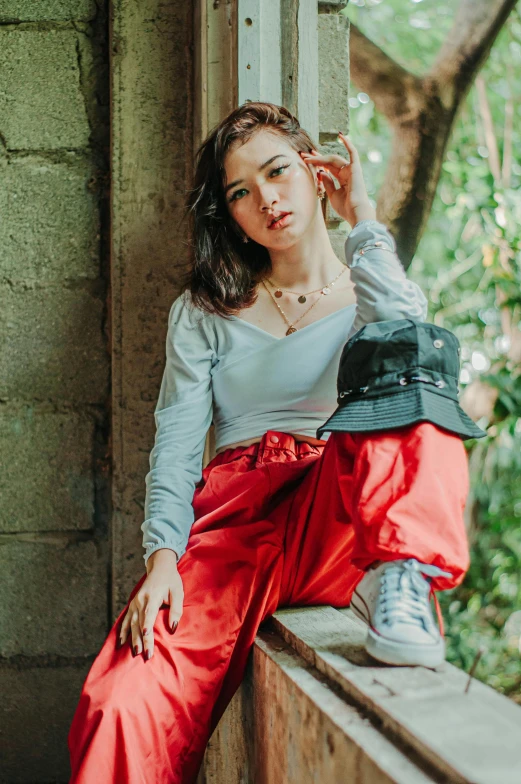 a woman sitting on top of a window sill, inspired by Ruth Jên, trending on pexels, visual art, wearing a red backwards cap, kuntilanak on tree, cropped shirt with jacket, satisfied pose