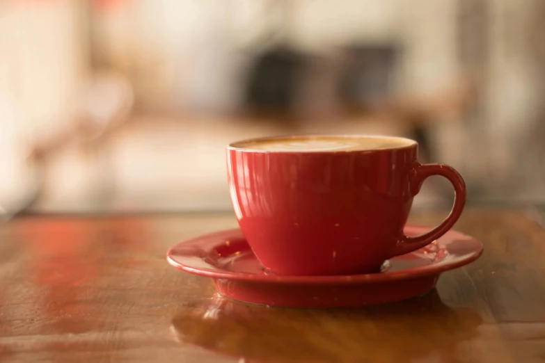 a cup of coffee sitting on top of a wooden table, pexels contest winner, pale red, all red, creamy, cafe