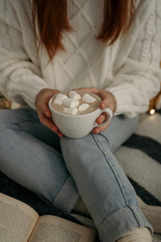 a woman sitting on a bed holding a cup of hot chocolate, inspired by Elsa Bleda, trending on pexels, marshmallow, 15081959 21121991 01012000 4k, hugging, made of glazed