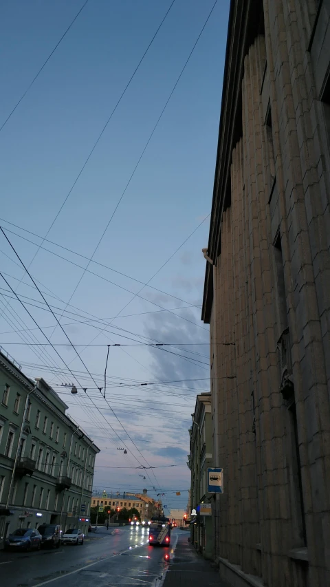 a street filled with lots of traffic next to tall buildings, an album cover, by Andrei Kolkoutine, unsplash, cable electric wires, saint petersburg, low quality photo, late summer evening