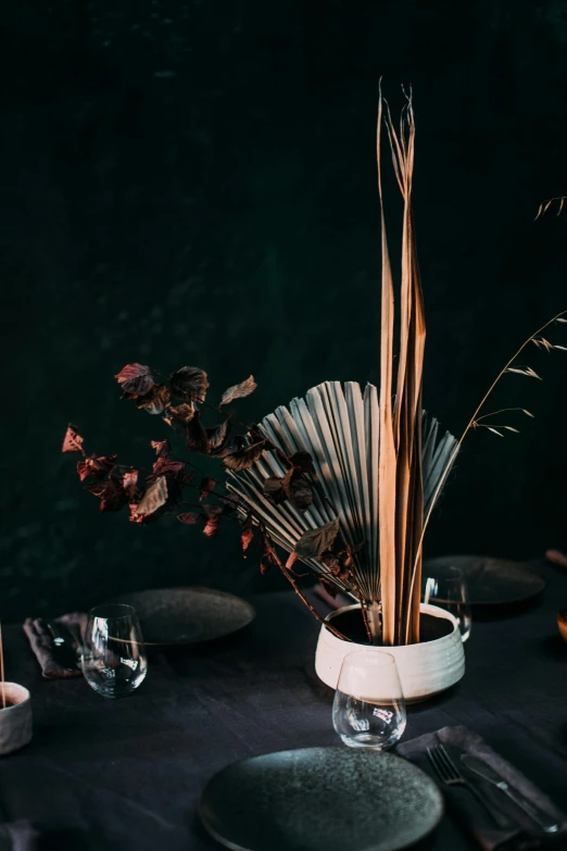 a black table topped with plates and silverware, an abstract sculpture, inspired by Constantin Hansen, trending on unsplash, renaissance, wild foliage, dried palmtrees, medium close up shot, detailed product image