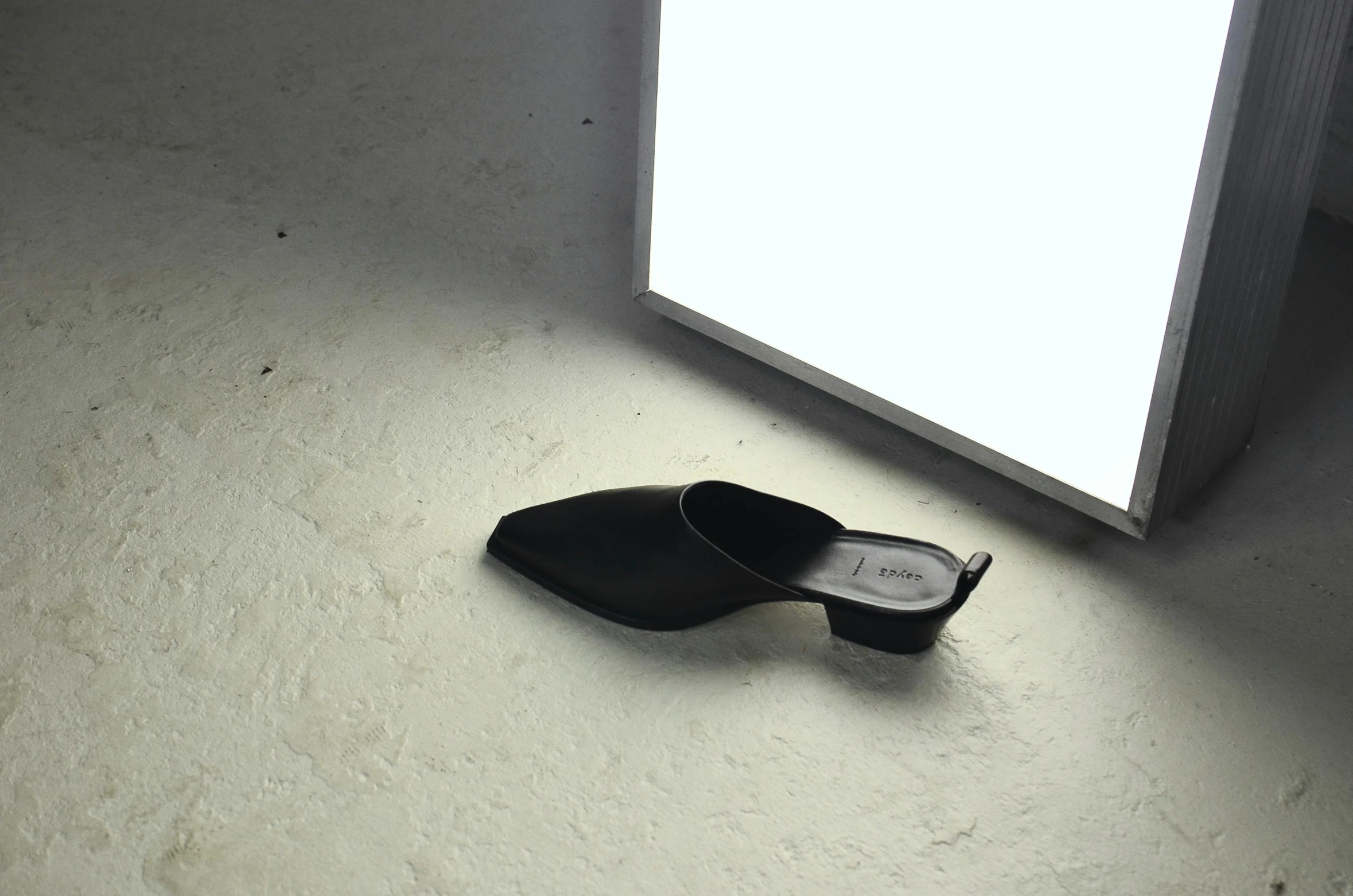 a pair of black shoes sitting in front of a light, inspired by Robert Mapplethorpe, unsplash contest winner, photorealism, clogs, issey miyake, product view, nanae kawahara