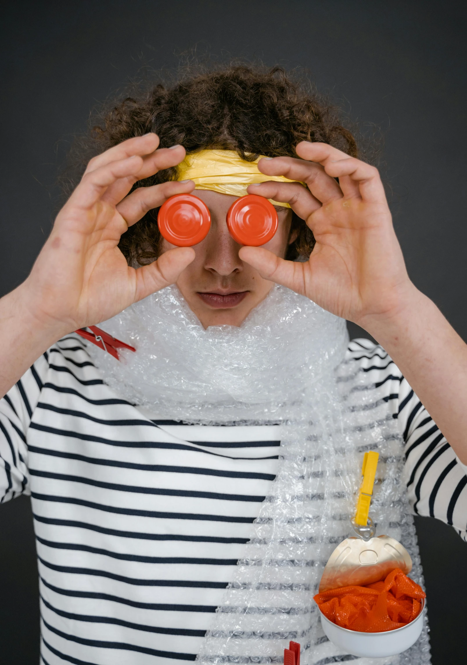 a man in striped shirt covering his eyes with food, an album cover, inspired by Sarah Lucas, trending on unsplash, plasticien, glass bubble helmet, made of lab tissue, also tomato, girl with warship parts