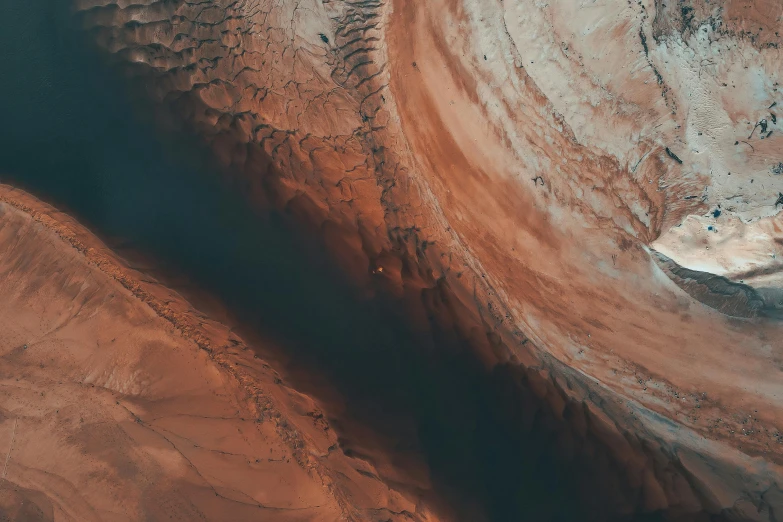 an aerial view of a body of water, inspired by Filip Hodas, pexels contest winner, hurufiyya, in a dusty red desert, swirling flows of energy, unsplash photography, moody mining planet