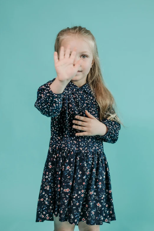 a little girl making a stop sign with her hands, antipodeans, floral patterned skin, photo from a promo shoot, navy, large tall