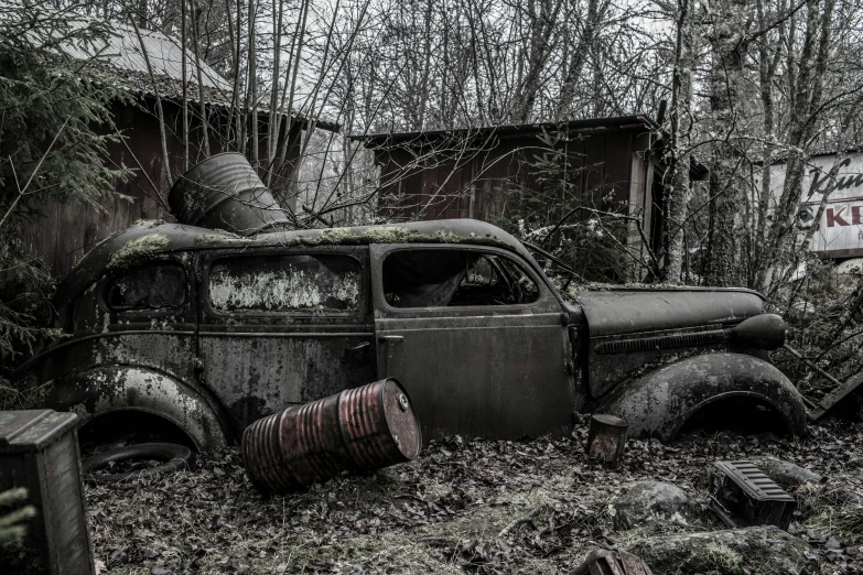 an old car sitting in the middle of a forest, by Adam Szentpétery, pexels contest winner, auto-destructive art, 9 steel barrels in a graveyard, in front of a garage, 1 9 4 0's, soviet suburbs